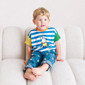 Kind, das das gestreifte „Move“-Kinder-T-Shirt mit Rippkragen in der Farbe Miffy trägt